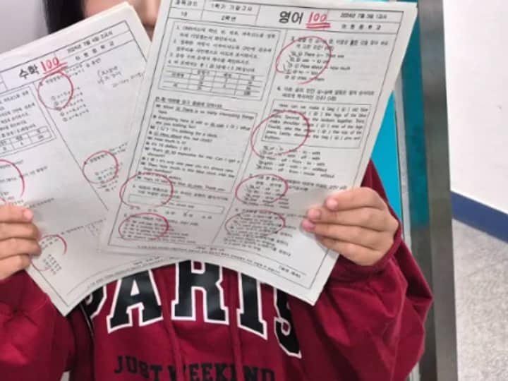 한맥학원 로고 앞에서 수학 100점, 영어 100점 시험지를 든 학생